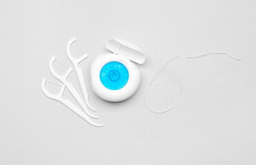 Dental floss and toothpicks on grey background