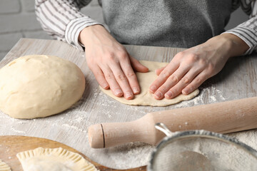 Fototapeta premium Woman making chebureki at wooden table, closeup