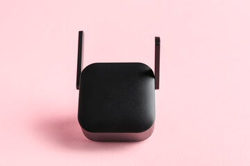 Black WiFi repeater on pink background