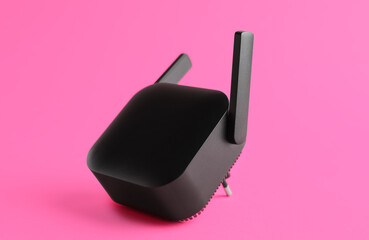 Black WiFi repeater on pink background