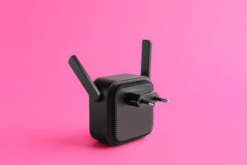 Black WiFi repeater on pink background