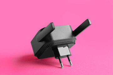 Black WiFi repeater on pink background
