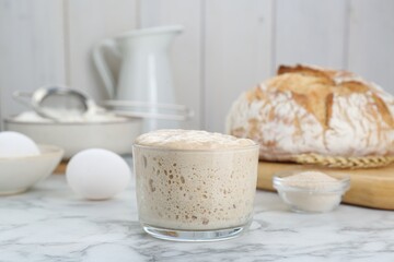 Glass jar with sourdough on white marble table