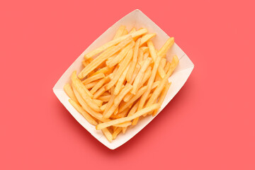 Paper box with tasty french fries on red background