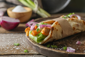 Delicious pita wrap with meat and vegetables on wooden table, closeup. Space for text