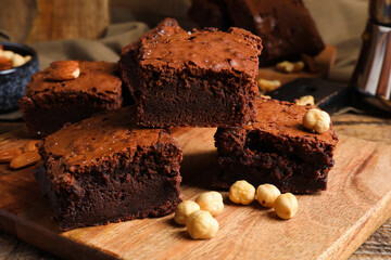 Board with pieces of tasty chocolate brownie on wooden table
