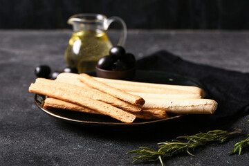 Plate with tasty Italian Grissini on dark background