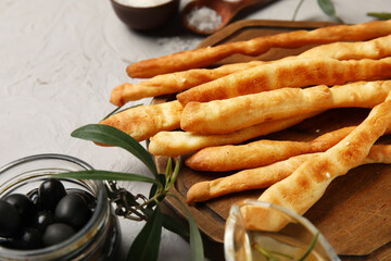 Wooden board with tasty Italian Grissini on light background, closeup