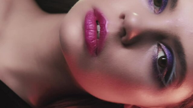 Vertical video. 90s look. Fashion makeup. Retro party vogue. Closeup portrait of confident teen girl model face with purple color eyeshadow pink lips artistic visage.