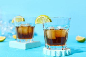 Glasses of cold rum with lime on blue background