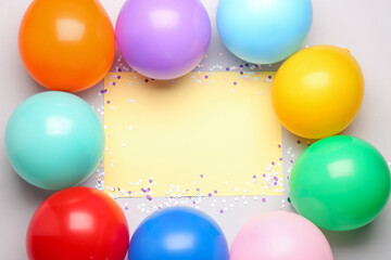 Frame made of colorful balloons and serpentine with blank paper sheet on grey background