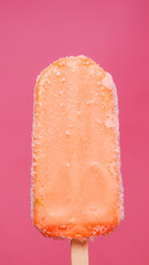 Close-up shot vertical of a bright orange popsicle stick.
