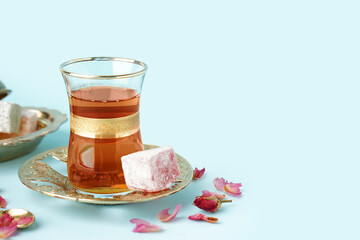 Glass of tea and Turkish delight on light blue background