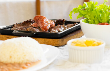 prepared dish, rice, beans, farofa, meat, sausage and salad on a table.