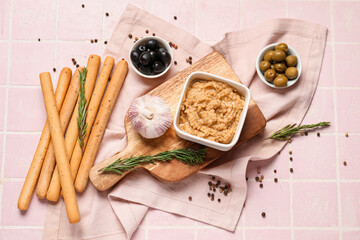 Bowl with hummus and tasty Italian Grissini on pink tile background