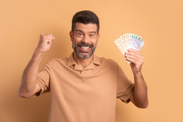 excited bearded man celebrating successful business money in beige background. finance, investment,...