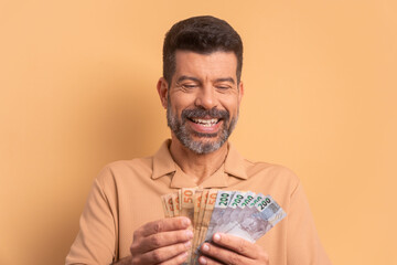 trustworthy senior man with brazil banknotes currency in studio shot. finance, investment, offer, loan concept. 