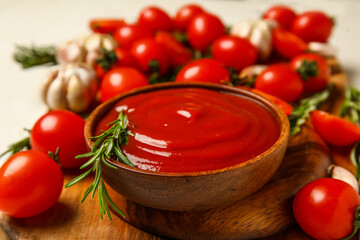 Bowl with tasty ketchup and fresh vegetables on light background, closeup