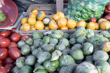 Some piles of yellow, green and red tomatoes on a street market stall