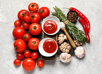 Bowls with tasty ketchup and fresh vegetables on light background