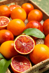 Wicker box with tasty blood oranges on green grunge background, closeup
