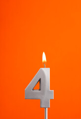 Number 4 - Burning anniversary candle on orange foamy background