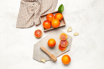 Box and board with tasty blood oranges on white background