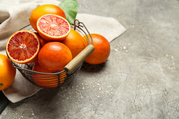 Metal basket with tasty blood oranges on grey background