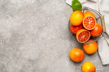 Metal basket with tasty blood oranges on grey background
