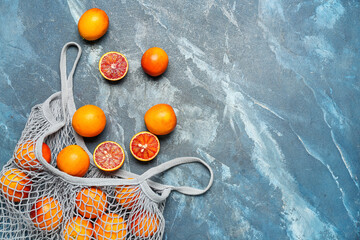 Mesh bag with tasty blood oranges on blue grunge background