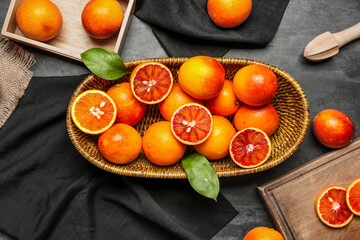 Wicker basket with tasty blood oranges on dark background