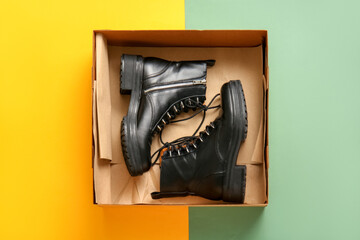 Cardboard box with stylish shoes on color background