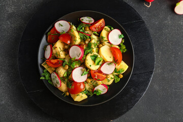 Plate of tasty Potato Salad with vegetables on dark background