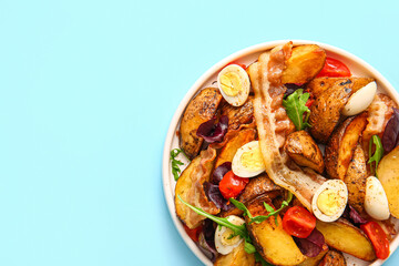 Plate of tasty potato salad with eggs, tomatoes and bacon on light blue background, top view