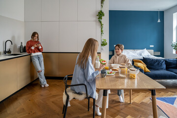 Smartphone addiction among teenagers. Teen girl standing with smartphone in kitchen, refusing to...