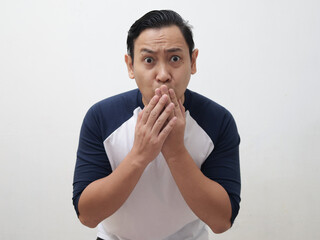 Asian man shocked and worried to see something bad, covering his mouth with hands and big eyes...