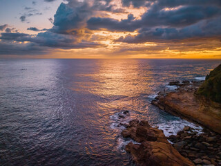 Obraz premium Ocean sunrise with clouds, rock and people fishing of the rock platform