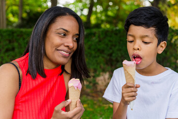 Mother and son enjoying eating ice-cream together outdoors in a park.