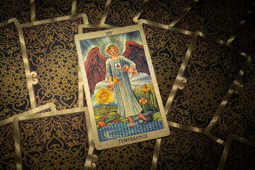 Gold embossed tarot cards on the table. The Major Arcana card The Temperance lies facing the viewer.