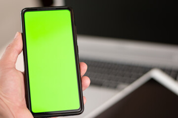 Horizontal view of cell phone with green chroma key in the screen with a laptop and tablet device...
