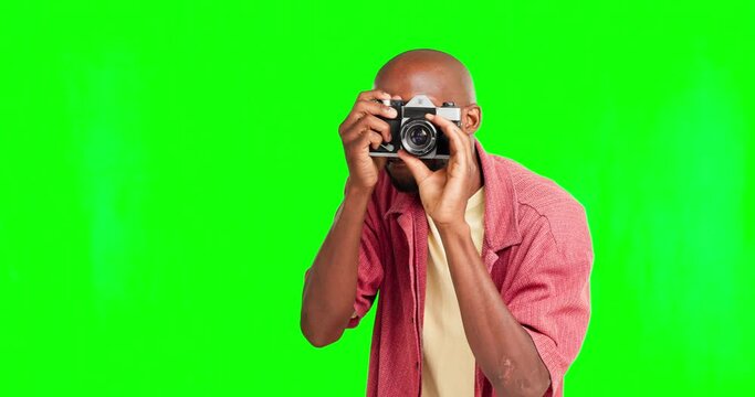 Photographer, camera with a black man on a green screen background in studio for photography. Fashion, magazine and photo shoot with male giving direction while taking a freelance photograph
