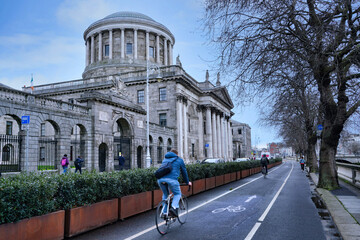 Dublin has a lot of cyclists, who make use of a large network of bike lanes, such as this one beside the River Liffey in front of the Four Courts - obrazy, fototapety, plakaty