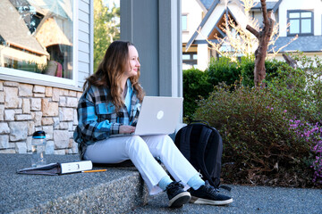 teenage girl sitting on porch in hands with phone she has white jeans blue blouse backpack with...