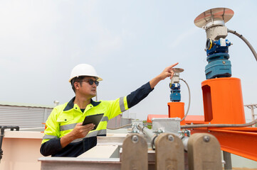 Industrial plumbing, overworked engineer wearing protective clothing and helmet on head while standing in industrial plant inspecting water supply system