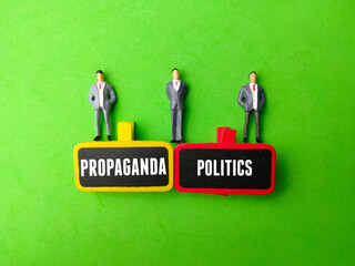Miniature people and wooden board with the word PROPAGANDA POLITICS