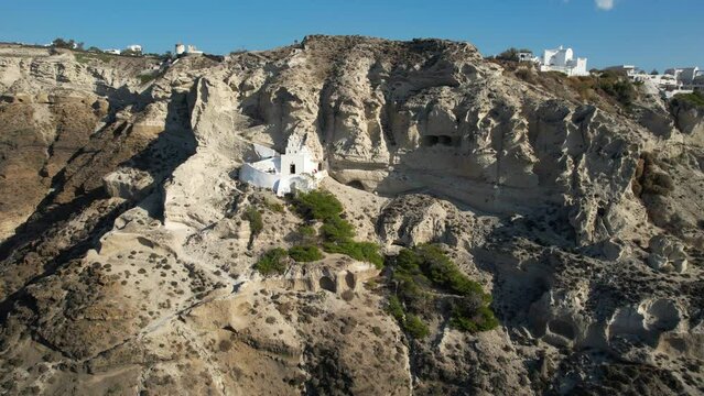Santorini Island, Greece. Drone Aerial View of Small Orthodox Church Under Rocky Cliffs