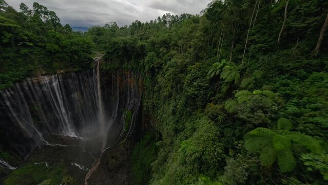 Dynamic wallride dive shot tropical island waterfall speed water fall stream stones mountain valley aerial view. FPV sport drone extreme exotic jungle cascade fern greenery cliff creek pool scenery 4k