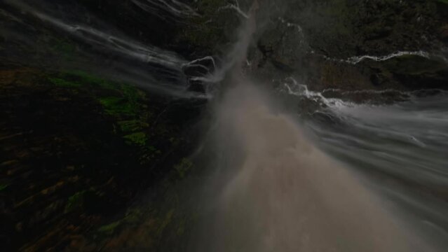 Extreme close dive tropical island waterfall speed water fall stream rainforest mountain valley aerial view. FPV sport drone drop shot exotic jungle fern greenery woodland cliff creek pool scenery 4k