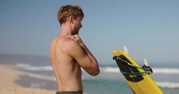 Surfer man putting a sunscreen on his face and neck