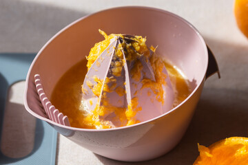 Manual plastic citrus juicer with a raw halved oranges on cutting board on the kitchen table....
